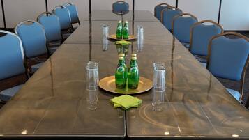 A conference room with a long table, blue chairs, and green bottles on the table.
