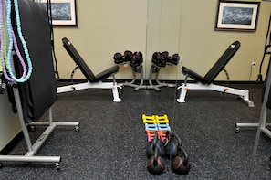 A gym with weightlifting equipment, benches, and a mirror.
