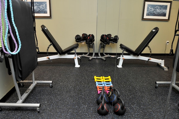 A gym with weightlifting equipment, benches, and a mirror. - Two-Queen Studio Suite w/ Daily Breakfast + Pool (St. Petersburg)