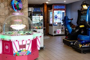 Eine Spielhalle mit verschiedenen Spielautomaten, darunter ein Skeeball-Spiel, eine Dartscheibe und ein Rennspiel.