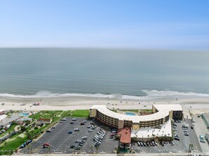 Ein Hotel an der Küste mit Parkplatz, Pool und Blick auf den Strand.