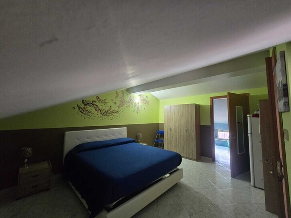 A bedroom with a bed, a wardrobe, and a door leading to another room. - Vrbo Property (Riposto)