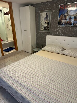 A bedroom with a bed, a wardrobe, a shower, and a wall with a poster. - The Heart of Old Town (Split)