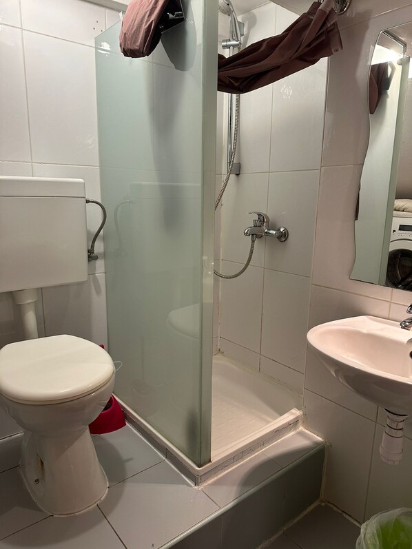 Een badkamer met toilet, douchecabine en wastafel.