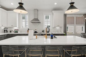 A modern kitchen with a large island, white cabinets, stainless steel appliances, and pendant lighting. - 4BR Escape for 12, East Nash Walkable Location! (Nashville)