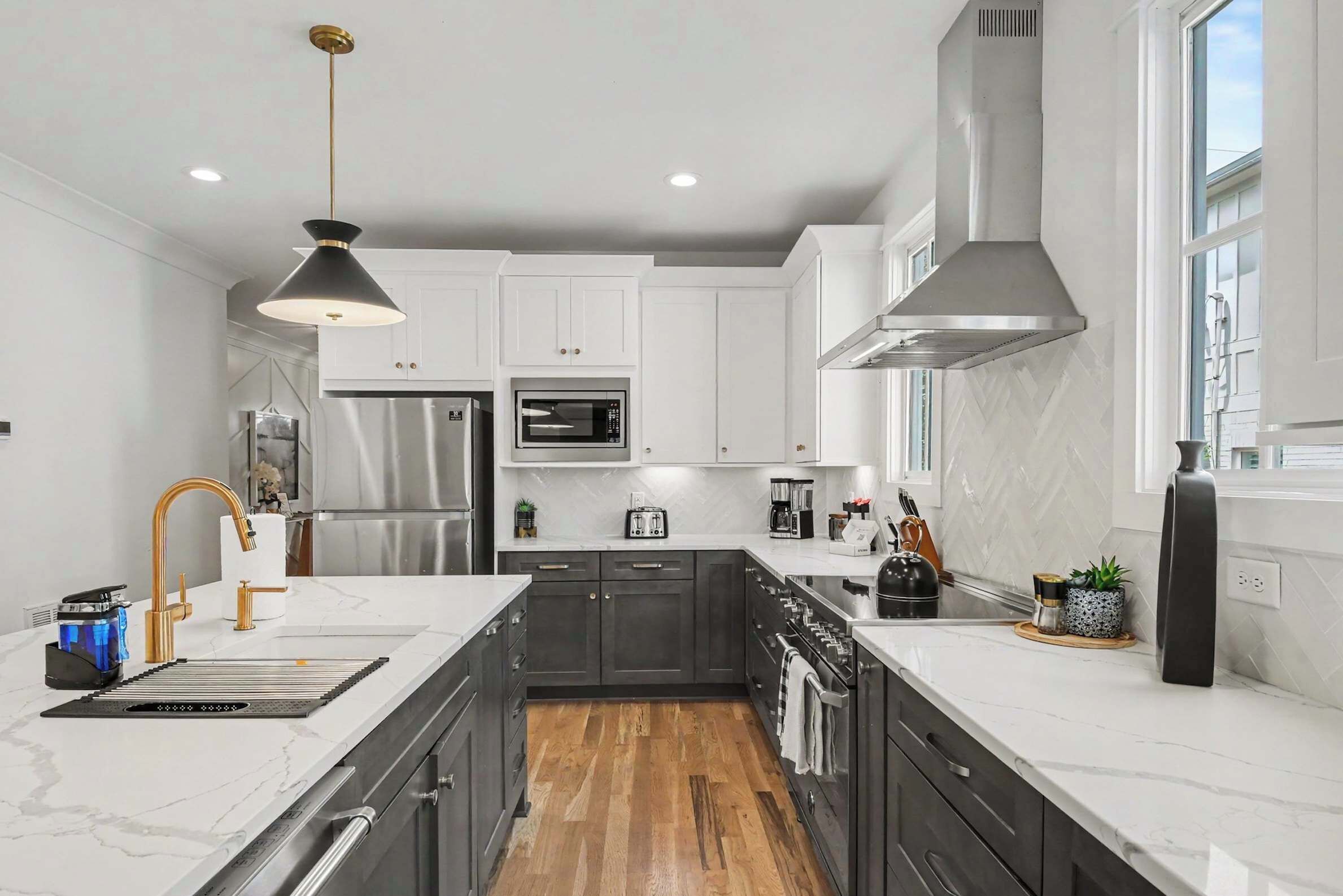 A modern kitchen with a central island, stainless steel appliances, and a large window providing natural light.