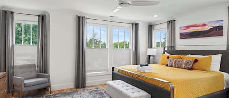 Ein Schlafzimmer mit einem Bett, einem Sessel, einer Bank und einem Deckenventilator.