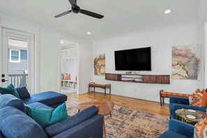 A modern living room with a flat-screen TV, blue sofas, a coffee table, and artwork on the walls. - 4BR Escape for 12, East Nash Walkable Location! (Nashville)