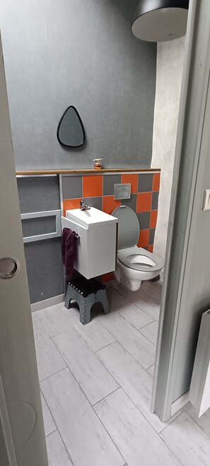 A bathroom with a toilet, sink, and a mirror. - Charming stone house with a garden – Finistère, near the sea (Quéménéven)