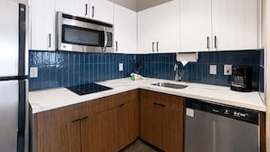 A modern kitchen with white cabinets, a stainless steel microwave, a dishwasher, and a coffee maker.