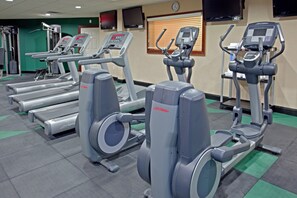 Un gimnasio con cintas de correr, elípticas y máquinas de pesas.