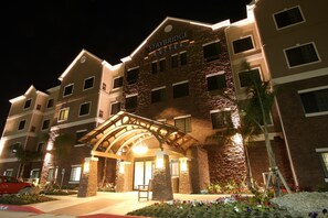 A Staybridge Suites hotel with a stone facade, multiple balconies, and a well-lit entrance.