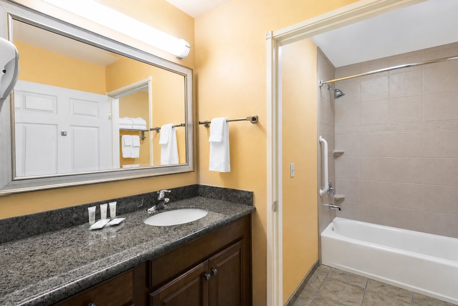 Baño con lavamanos, espejo, toallero y zona de ducha.