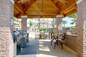 An outdoor patio with a barbecue area, stone walls, and outdoor seating.