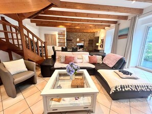 A modern living room with a glass coffee table, leather sofas, and a stone fireplace.