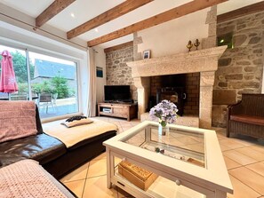 A living room with a stone fireplace, a sofa, a coffee table, and a television.