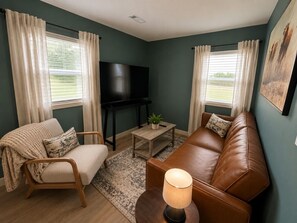 Ein Wohnzimmer mit einer Couch, einem Sessel, einem Couchtisch und einem Fernseher.