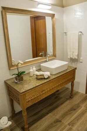 A bathroom with a wooden vanity, a large mirror, a white sink, and a towel rack.