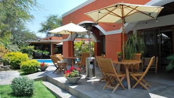 Une terrasse extérieure avec des tables et des chaises en bois, des parasols et des plantes en pot.