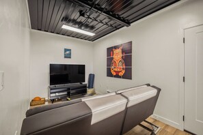 Una sala de estar moderna con un televisor de pantalla plana, un sofá y una obra de arte colgada en la pared.