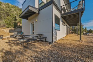 Une maison moderne dotée d’un patio, d’un espace salon extérieur et offrant une vue sur le paysage environnant.
