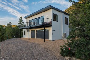 Una casa moderna de dos pisos con balcón, garaje y entrada de grava.