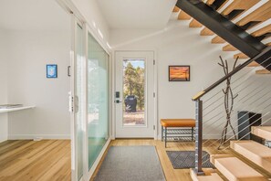 Ein modernes Interieur mit Glastür zu einem Balkon, einer Holztreppe und einer Bank.