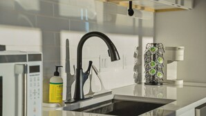 Eine moderne Küche mit einem schwarzen Wasserhahn, einer Mikrowelle und einer Kaffeemaschine.