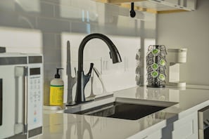 Eine moderne Küche mit einem schwarzen Wasserhahn, einer Mikrowelle und einer Kaffeemaschine.