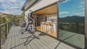 Eine moderne Terrassenanlage im Freien mit Schaukelstuhl, Bar und Blick auf die Berge.