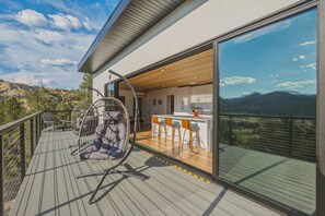 Eine moderne Terrassenanlage im Freien mit Schaukelstuhl, Bar und Blick auf die Berge.