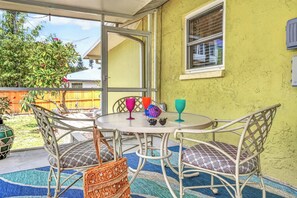 A covered patio area with a round table, chairs, and a woven basket. - Aloha Cottage at Sapphire Shores (Sarasota)