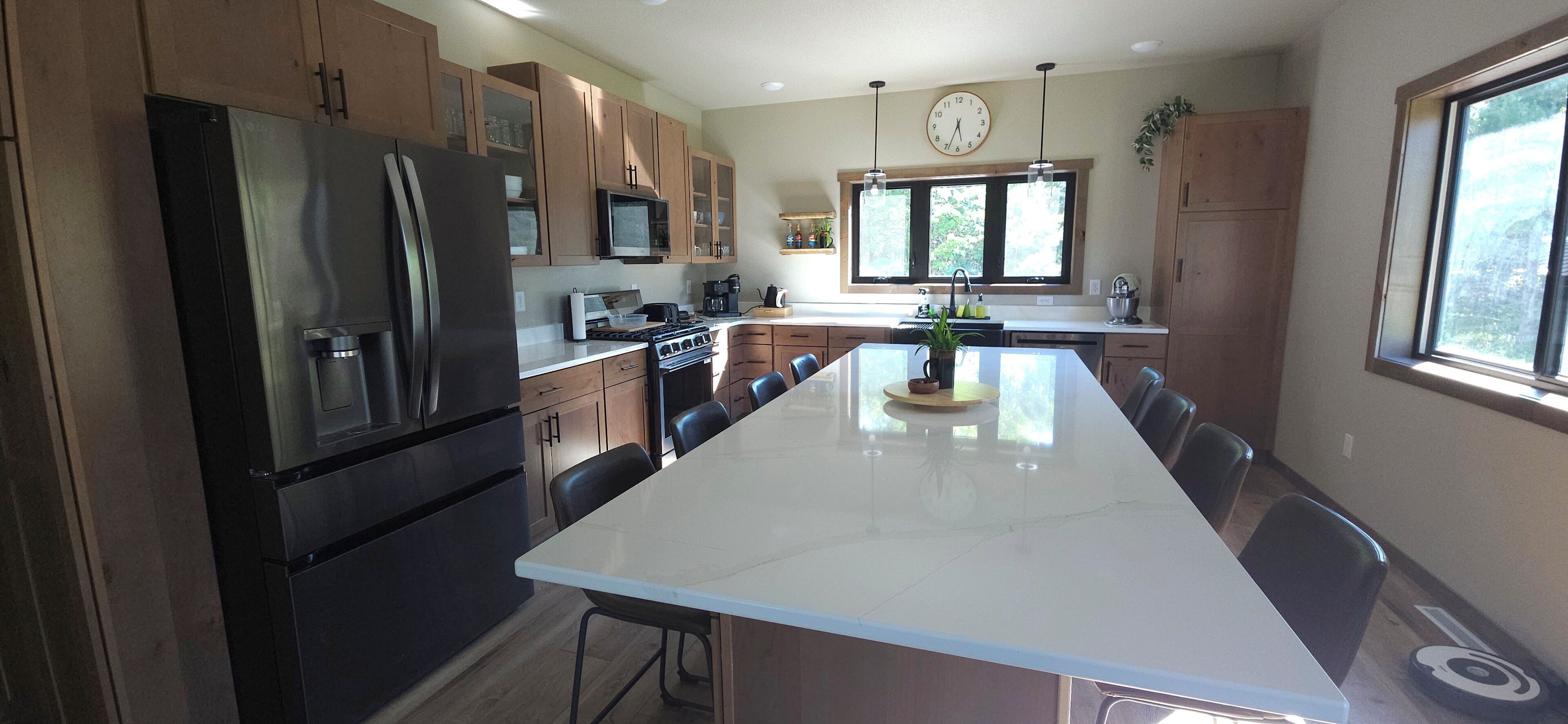 A modern kitchen with a central island, stainless steel appliances, and wooden cabinets.
