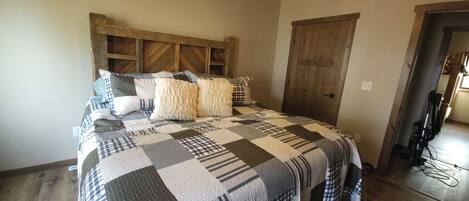 Une chambre avec une tête de lit en bois, une couvre-lit matelassée et une porte sur le côté droit.