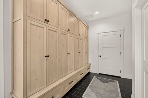 Ein Flur mit einem großen Holzschrank, einer Tür und einem schwarzen Fliesenboden.