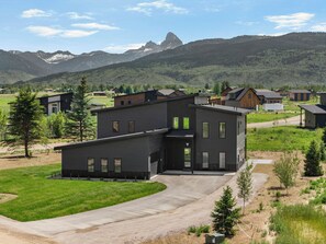 Ein modernes, zweistöckiges Haus mit Auffahrt und Blick auf Berge im Hintergrund.