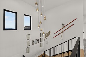 Eine Treppe mit schwarzer Geländer, eine Wand mit gerahmten Kunstwerken und ein Fenster mit Blick auf ein Gebäude.