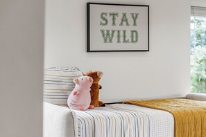 Ein Schlafzimmer mit einem Bett, Kissen, einem gerahmten Schild und Stofftieren.