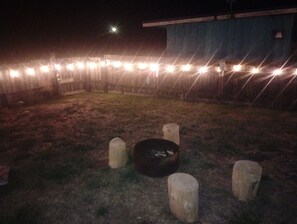 A fenced outdoor area with a fire pit and wooden posts.