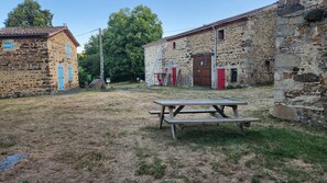 A rustic stone building with a wooden picnic table in the foreground. - Vrbo Property (Condat-lès-Montboissier)