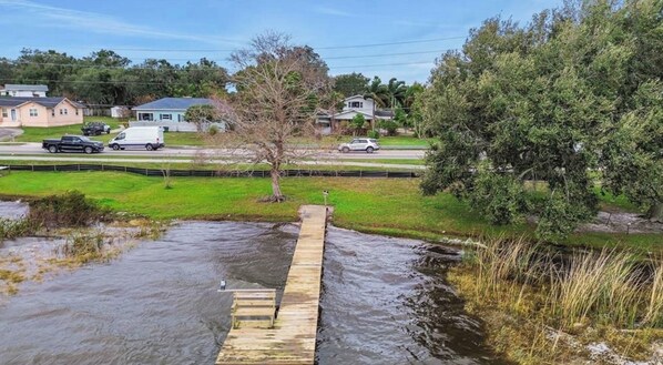 A residential area with a wooden bridge over a water body, surrounded by houses and greenery.