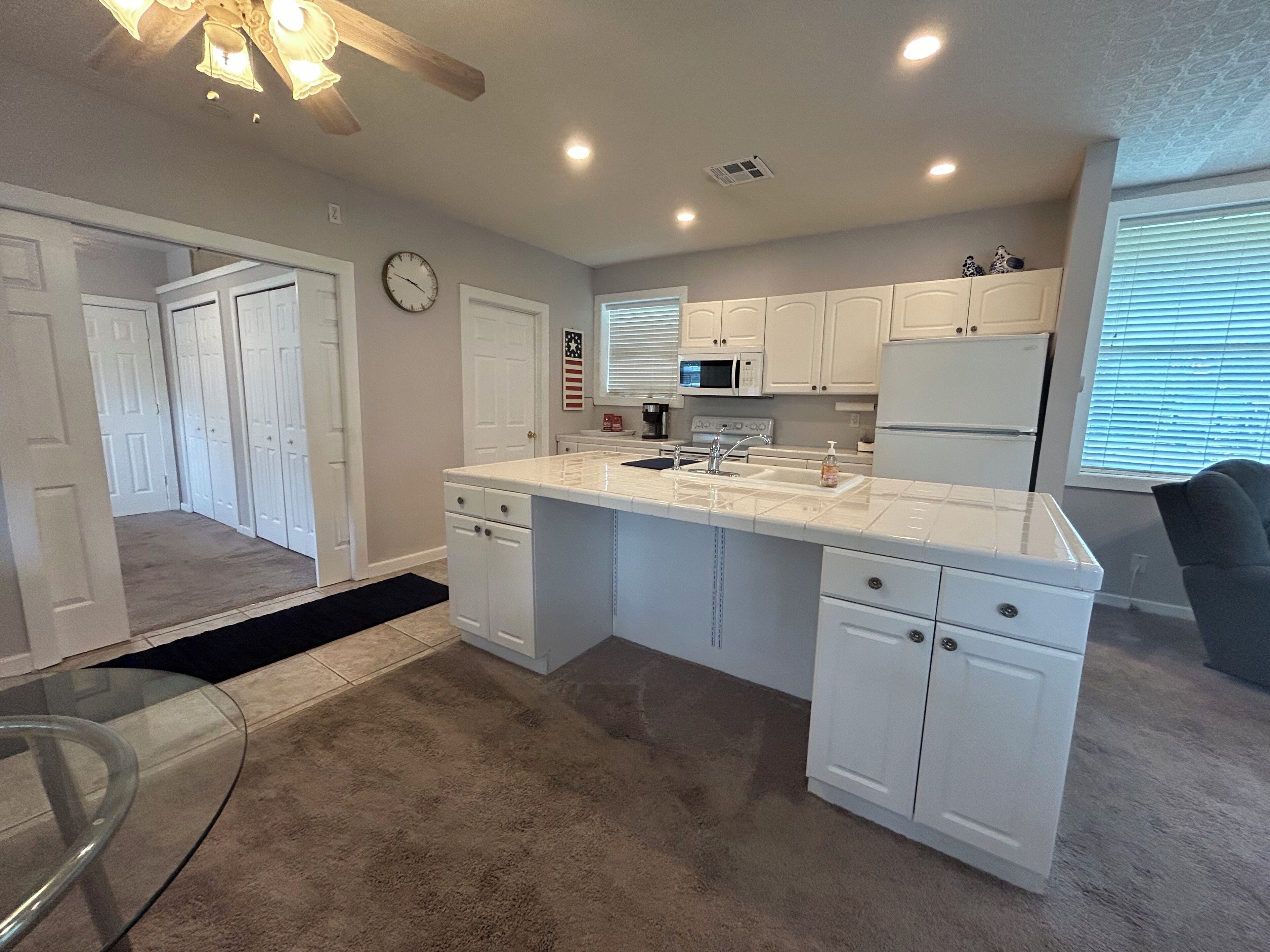 A modern kitchen with white cabinetry, a central island, and built-in appliances.