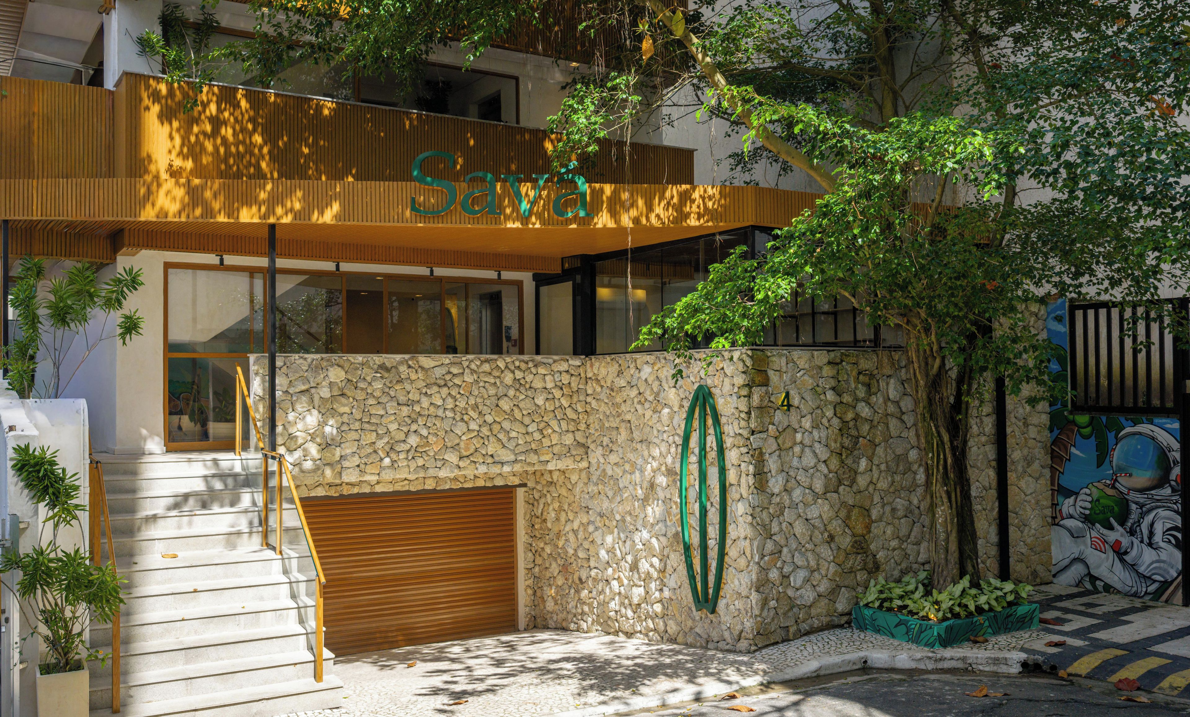 Un edificio moderno con fachada de piedra, un alero de madera y un logotipo verde.