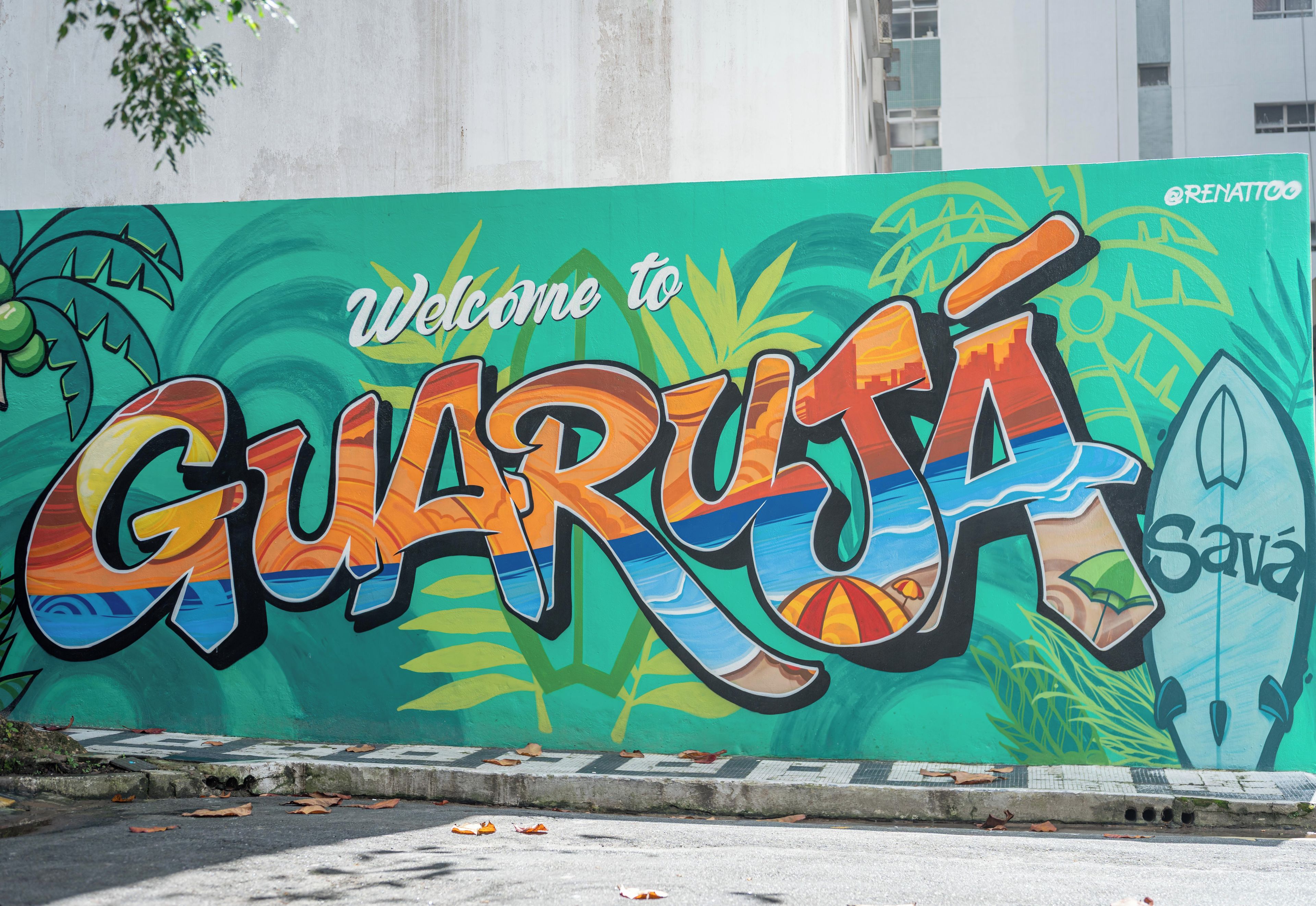 A colorful mural with the text 'Welcome to Guarujá' and a surfboard.