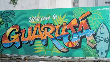 A colorful mural with the text 'Welcome to Guarujá' and a surfboard.