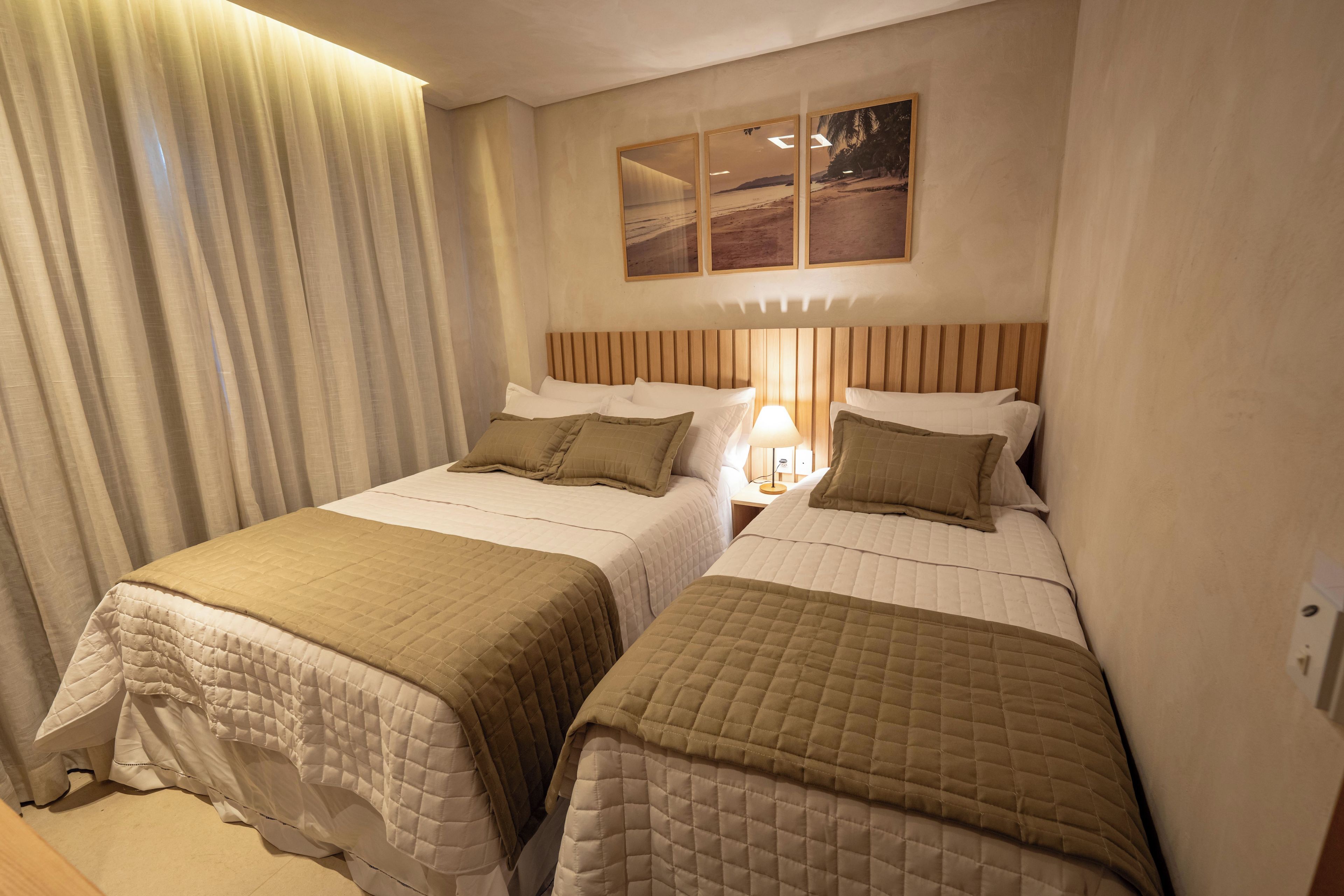 A hotel room with two beds, a nightstand with a lamp, and a painting on the wall.