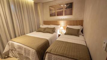A hotel room with two beds, a nightstand with a lamp, and a painting on the wall.