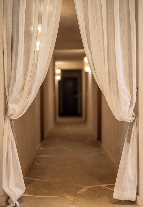 A corridor with a stone floor and white curtains tied at the ends.