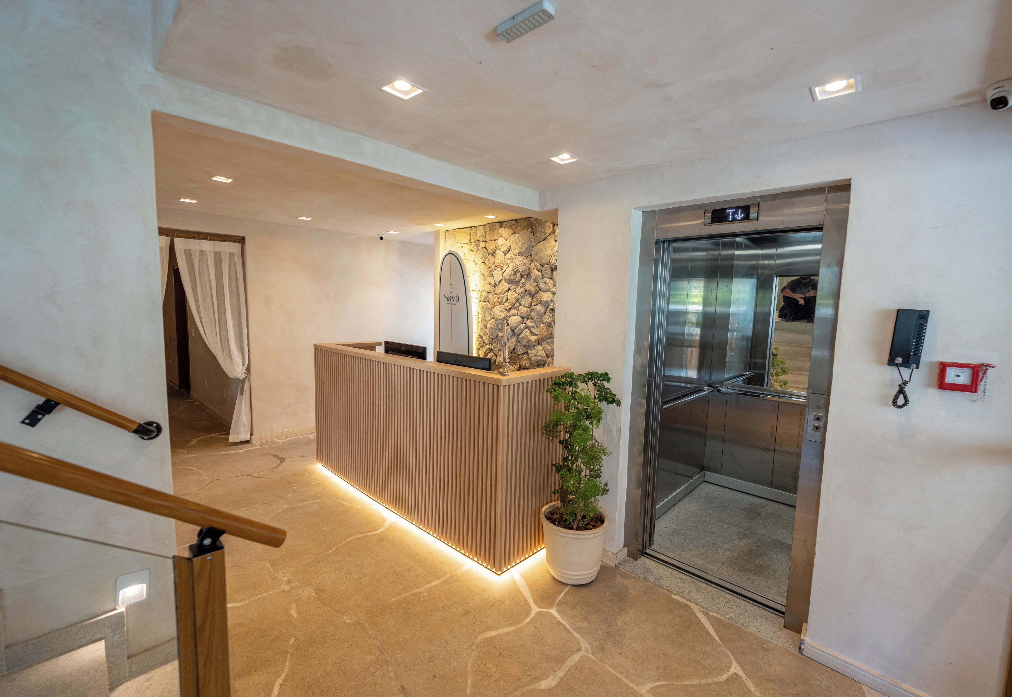 Una zona de recepción con un mostrador de madera, una pared de piedra y un ascensor.