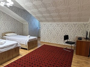 Een slaapkamer met twee bedden, een bureau, een stoel en een kamerbreed tapijt met dessin.